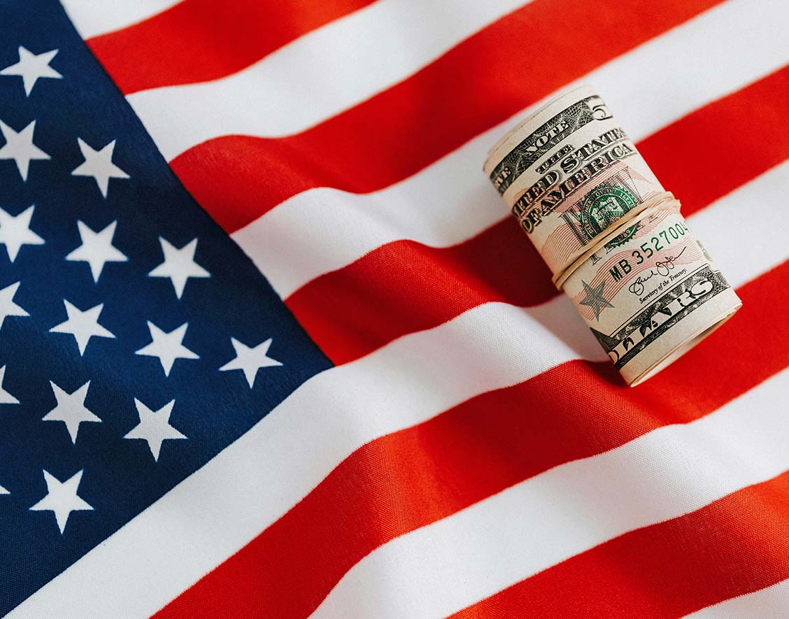 Roll of Dollar Bills on American Flag