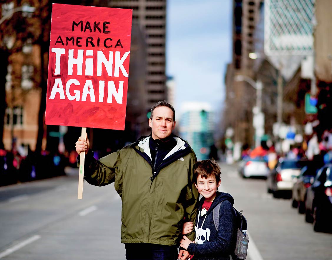 Father and Son in Street Holding up a Sign